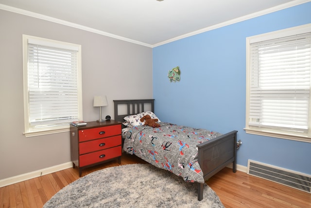 bedroom featuring visible vents, crown molding, and wood finished floors