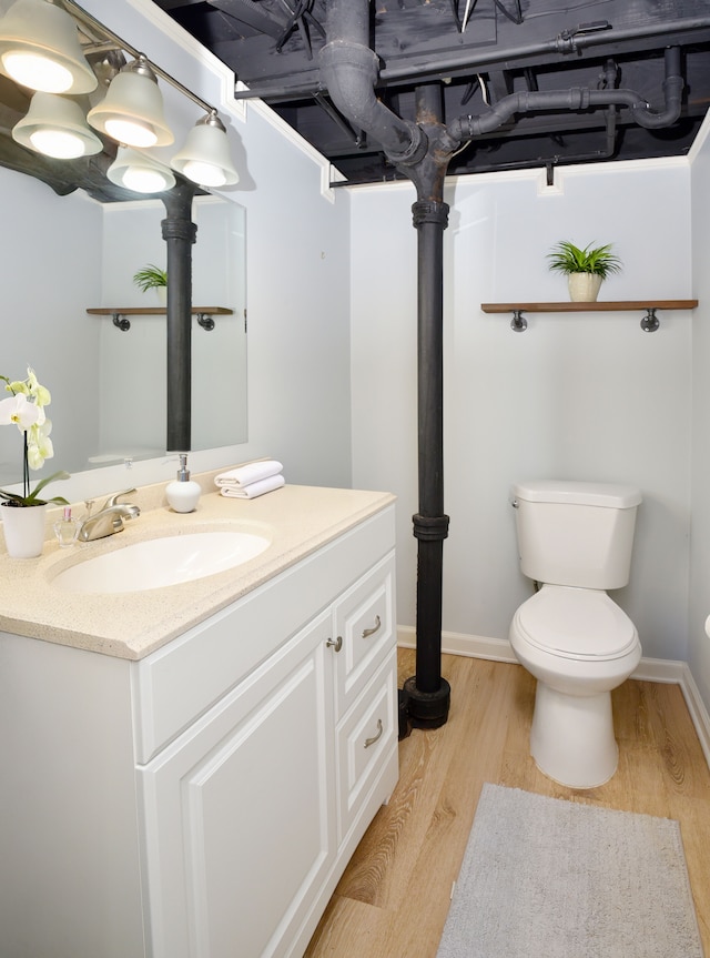 bathroom featuring toilet, vanity, baseboards, and wood finished floors