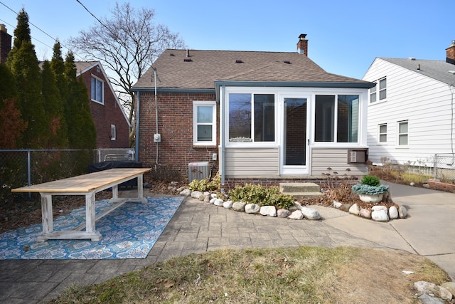 rear view of property featuring fence, a chimney, central air condition unit, a patio area, and brick siding