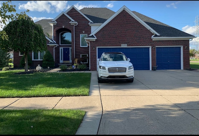 traditional-style home with concrete driveway, brick siding, a garage, and a front yard