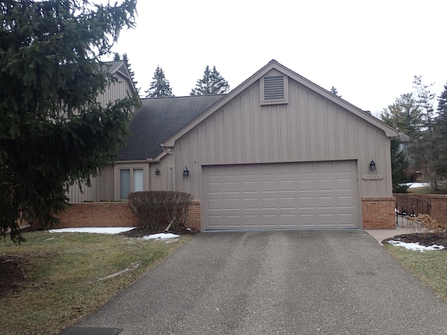 view of front of home with a garage, brick siding, roof with shingles, and driveway