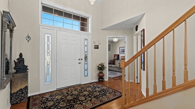 entrance foyer featuring stairs, wood finished floors, baseboards, and a towering ceiling