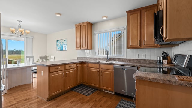 kitchen with light wood finished floors, a peninsula, a sink, range with electric stovetop, and stainless steel dishwasher