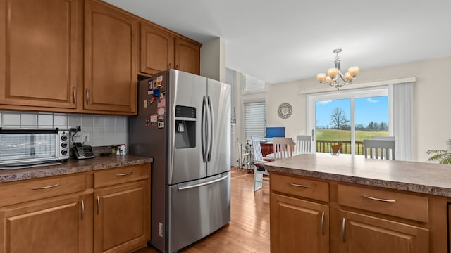 kitchen featuring brown cabinetry, backsplash, and stainless steel fridge with ice dispenser