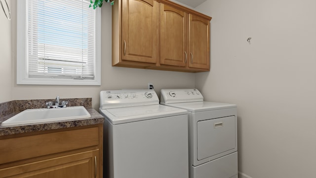 clothes washing area featuring a sink, cabinet space, and washing machine and clothes dryer