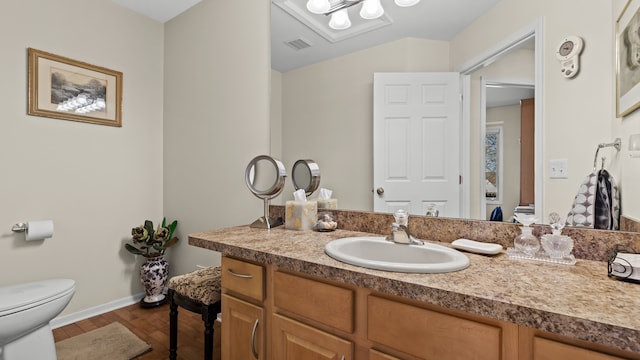 bathroom featuring visible vents, baseboards, toilet, wood finished floors, and vanity