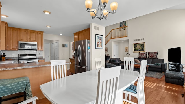 dining space with a chandelier, visible vents, stairs, and light wood-type flooring