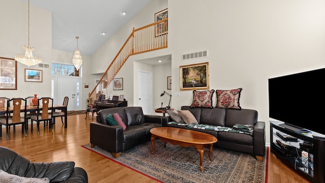 living room with a chandelier, visible vents, stairway, and wood finished floors