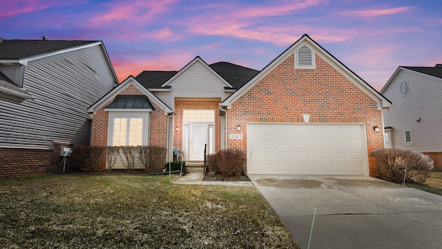 view of front of house featuring an attached garage, a lawn, brick siding, and driveway