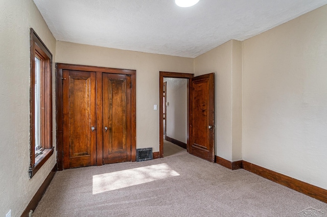 unfurnished bedroom with baseboards, visible vents, carpet floors, a closet, and a textured ceiling