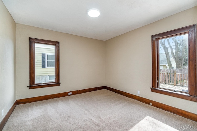 spare room with carpet flooring, baseboards, and a wealth of natural light