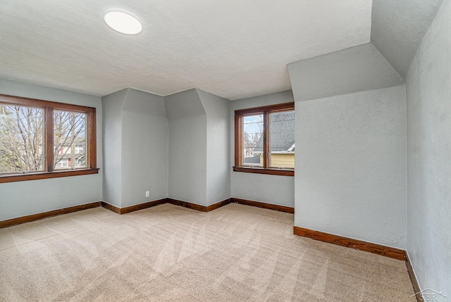 carpeted empty room with plenty of natural light, a textured wall, baseboards, and a textured ceiling