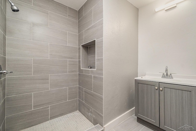 bathroom with tiled shower and vanity