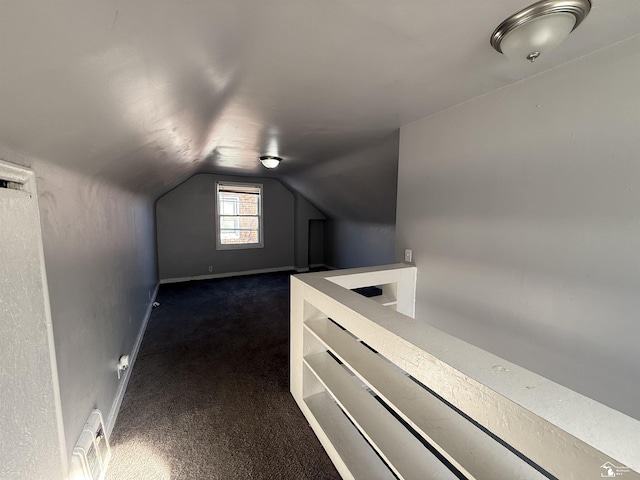 spacious closet with dark colored carpet, visible vents, and vaulted ceiling