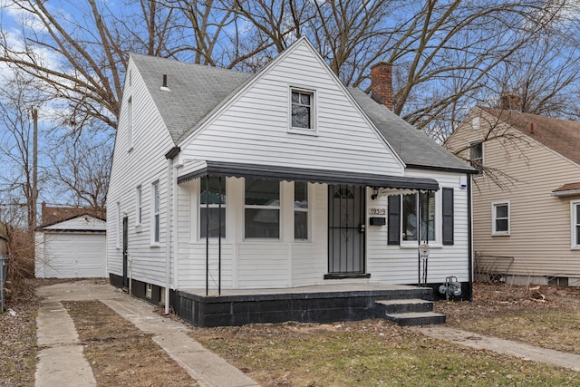 view of front of property with an outbuilding, a garage, roof with shingles, and a chimney