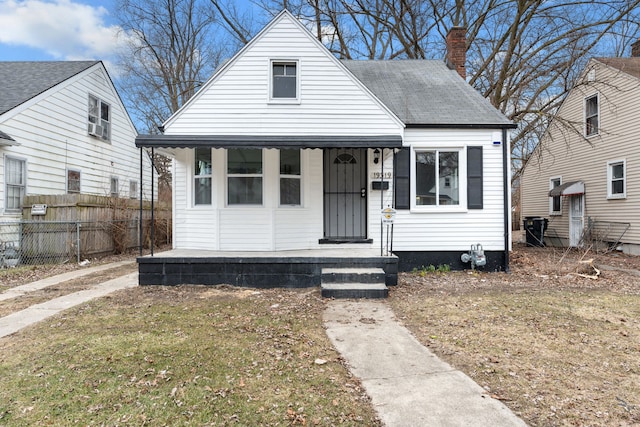 bungalow-style home featuring fence, covered porch, and a chimney