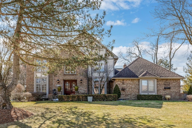 view of front of home with a front yard, a shingled roof, a chimney, french doors, and brick siding