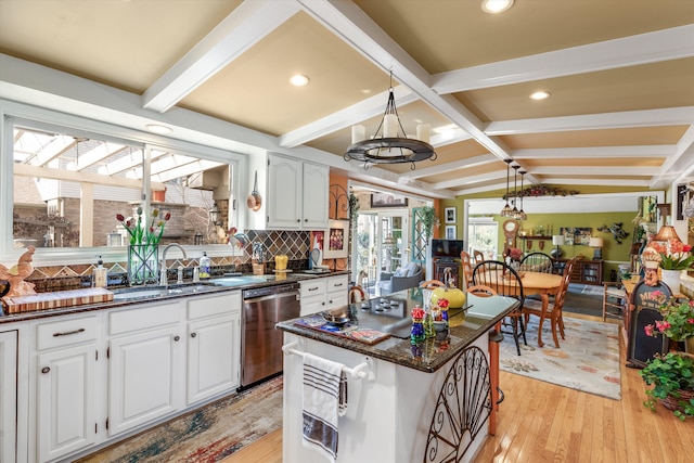 kitchen with tasteful backsplash, vaulted ceiling with beams, stainless steel dishwasher, light wood-style floors, and a sink