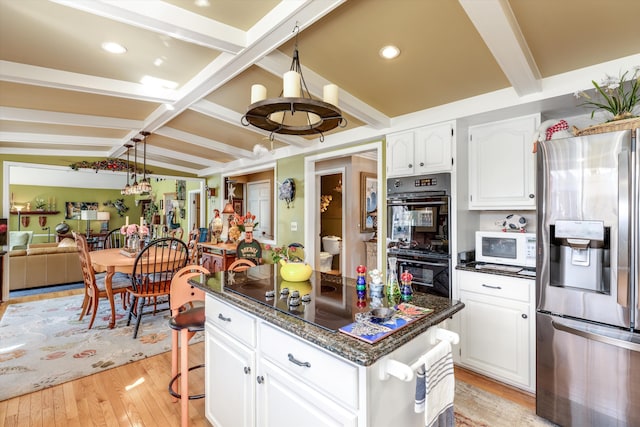 kitchen with beamed ceiling, black appliances, a kitchen island, white cabinetry, and light wood finished floors