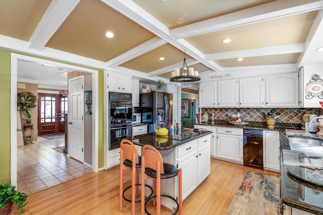 kitchen with black appliances, a sink, tasteful backsplash, a center island, and white cabinets