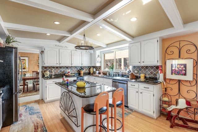 kitchen featuring beam ceiling, appliances with stainless steel finishes, a center island, and white cabinetry