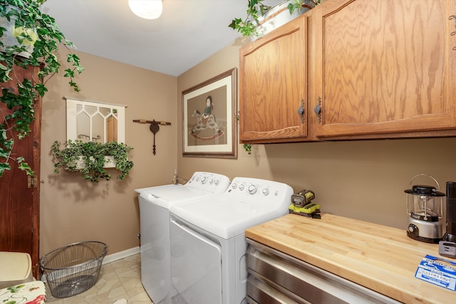 laundry area featuring washing machine and clothes dryer, cabinet space, and baseboards