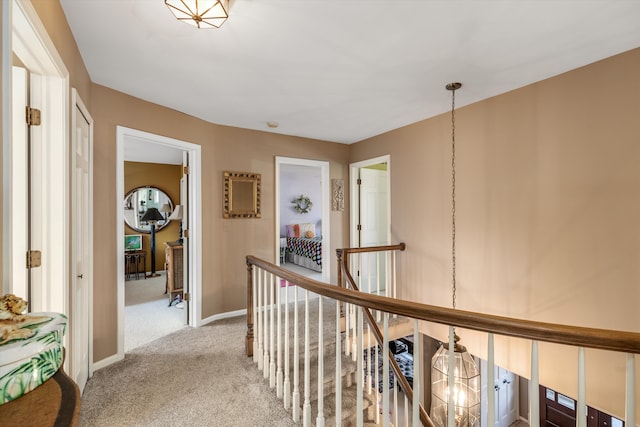 corridor featuring an upstairs landing, baseboards, and carpet