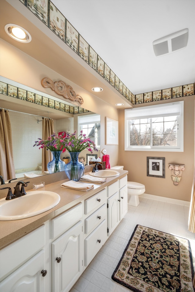 bathroom featuring double vanity, toilet, a wealth of natural light, and a sink