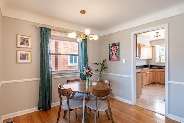 dining area featuring light wood-style floors, baseboards, a notable chandelier, and visible vents