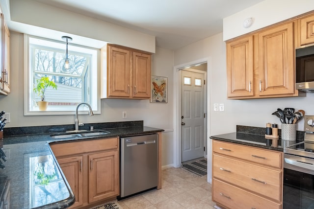 kitchen featuring dark stone countertops, decorative light fixtures, appliances with stainless steel finishes, and a sink