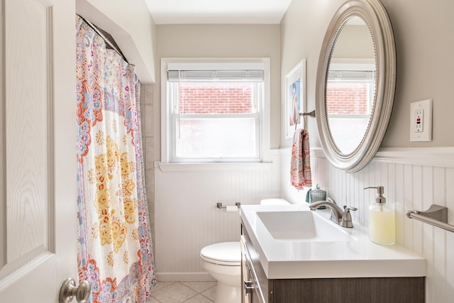 full bath featuring a shower with curtain, toilet, wainscoting, tile patterned flooring, and vanity