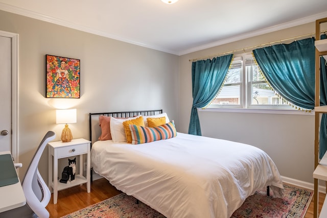 bedroom with wood finished floors, baseboards, and ornamental molding