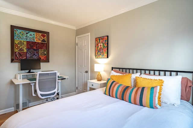 bedroom featuring visible vents, baseboards, wood finished floors, and crown molding