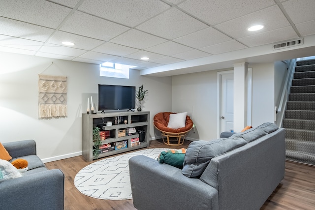 living area featuring visible vents, baseboards, stairway, wood finished floors, and a paneled ceiling