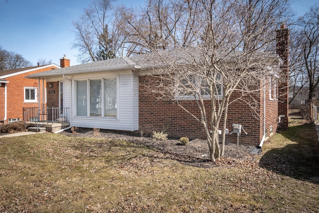 exterior space with a yard, brick siding, and a chimney