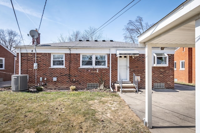 back of house with brick siding, a yard, and central AC