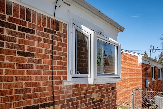 view of home's exterior with central AC unit, fence, and brick siding