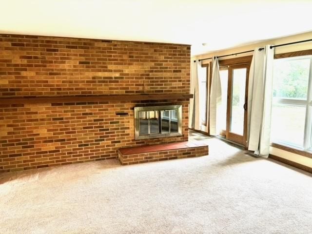 unfurnished living room with a brick fireplace and carpet