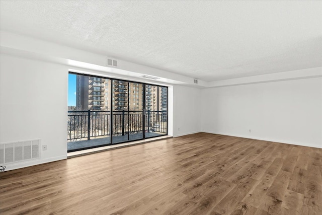 spare room featuring visible vents, a textured ceiling, and wood finished floors