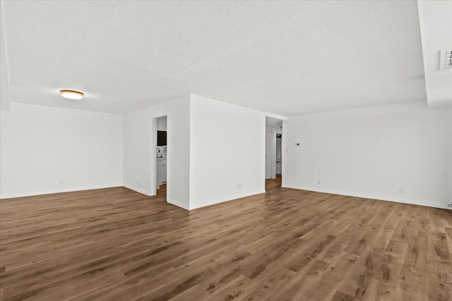 empty room featuring wood finished floors, visible vents, and a textured ceiling