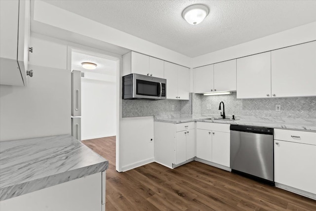 kitchen featuring a sink, dark wood finished floors, white cabinetry, appliances with stainless steel finishes, and decorative backsplash