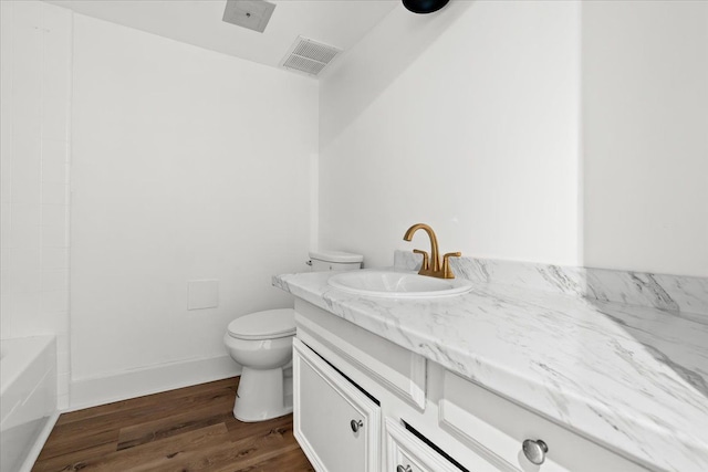 full bath featuring vanity, wood finished floors, visible vents, baseboards, and toilet