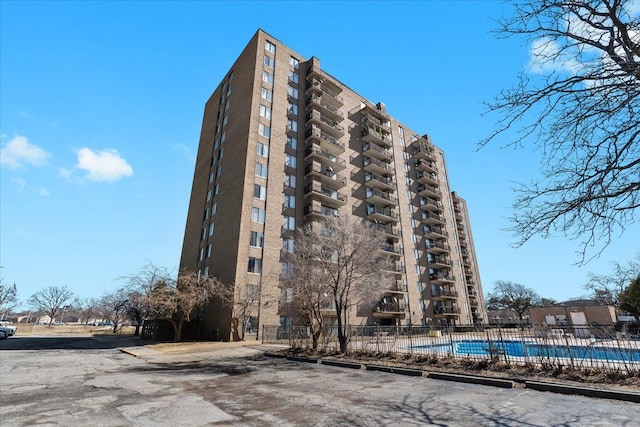 view of building exterior featuring a community pool and fence