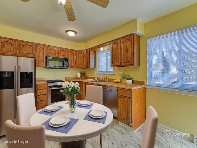 kitchen featuring brown cabinets, marble finish floor, a sink, appliances with stainless steel finishes, and light countertops