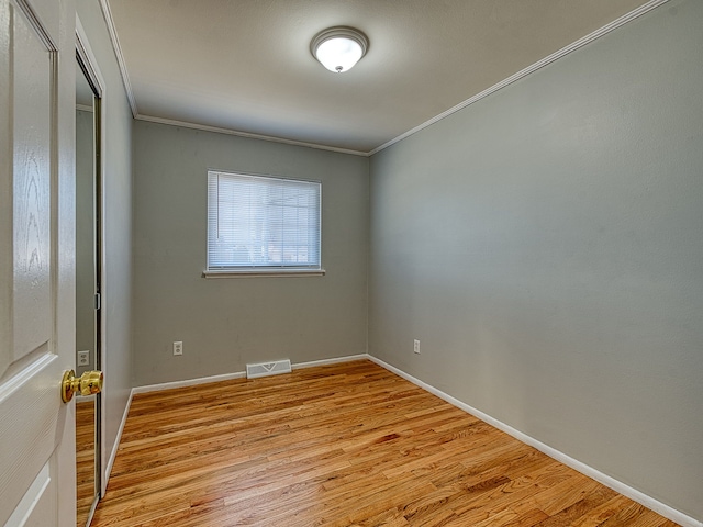 spare room featuring crown molding, baseboards, visible vents, and light wood-type flooring