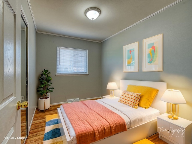 bedroom with visible vents, crown molding, baseboards, and wood finished floors