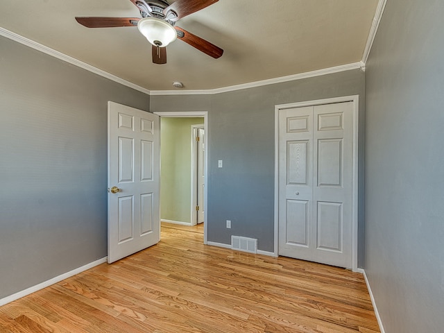 unfurnished bedroom with visible vents, ceiling fan, baseboards, ornamental molding, and light wood-style flooring