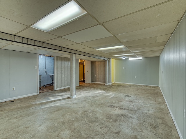 finished below grade area featuring a drop ceiling and baseboards