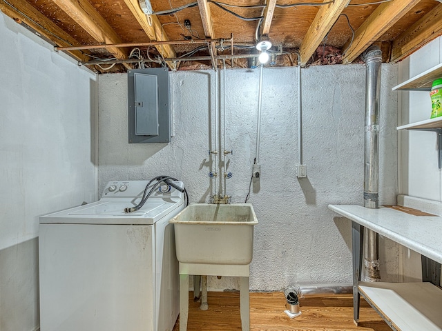 laundry area featuring wood finished floors, washer / dryer, laundry area, electric panel, and a sink