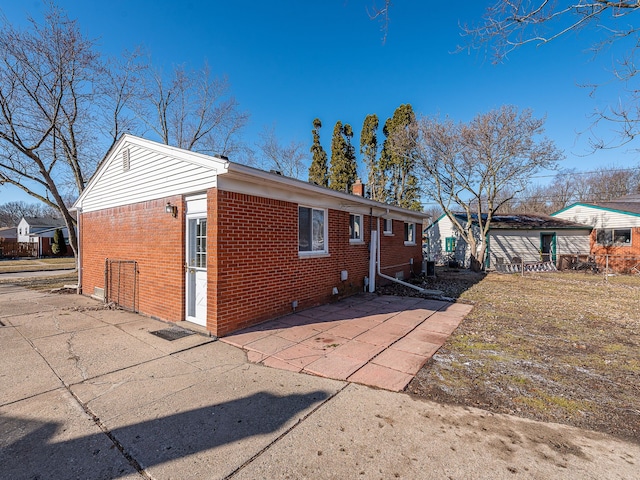 view of side of home featuring brick siding and a patio area